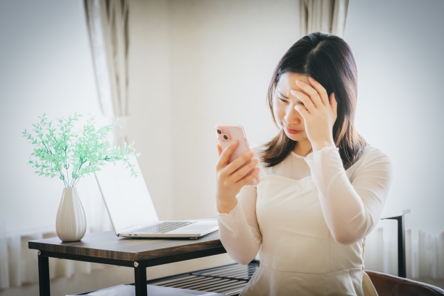 スマホを持って落ち込む女性